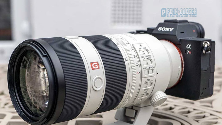 Белый телеобъектив Sony FE 70-200mm GM OSS II на камере Sony A7R со штативной лапкой стоит на ажурном столике на веранде